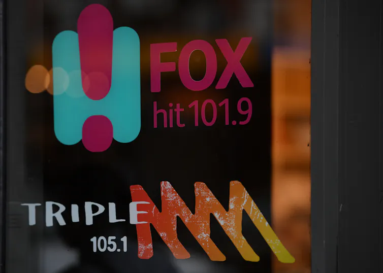 A glass panel with logos for radio stations called fox hit 101.9 and triple m 105.1
