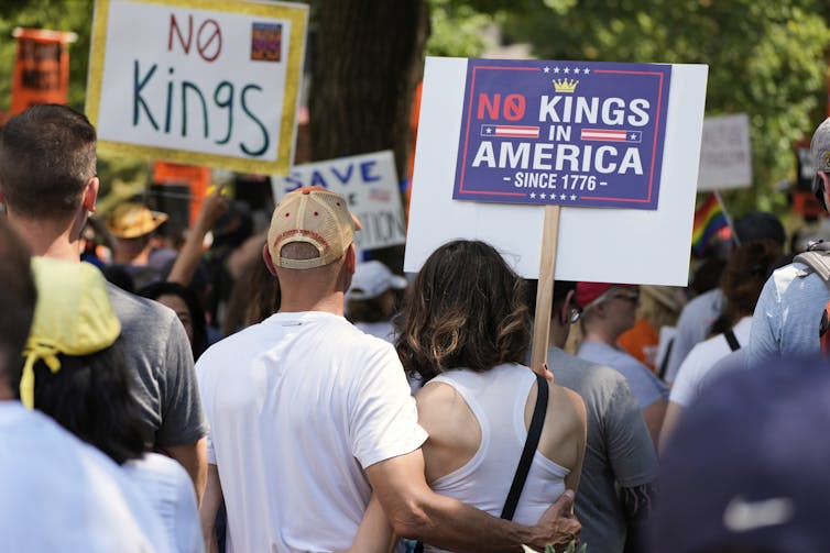 Activists carry signs during a protest against President Donald Trump's federal takeover of policing.