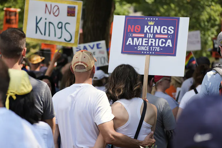 Activists carry signs during a protest against President Donald Trump's federal takeover of policing.