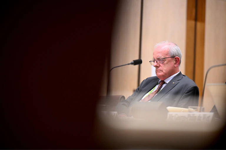 A man in glasses and a suit frowns