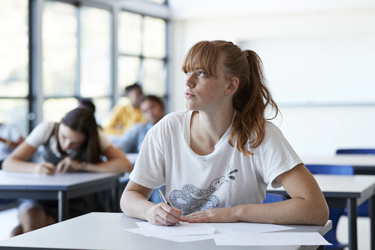 A young woman works at a table in an exam room.