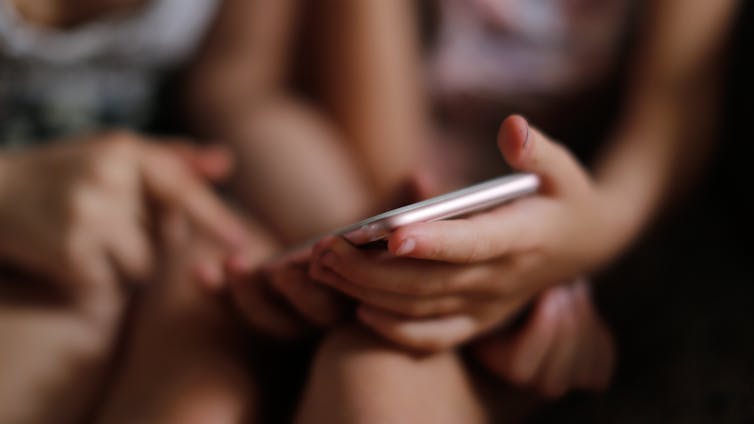 Children girls with a smartphone, children scare and threaten the phone.