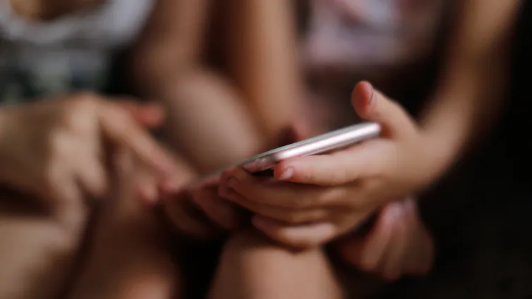 Children girls with a smartphone, children scare and threaten the phone.
