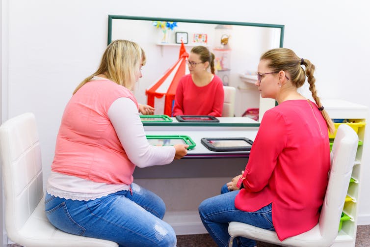 Two women sitting at a desk with tablets.