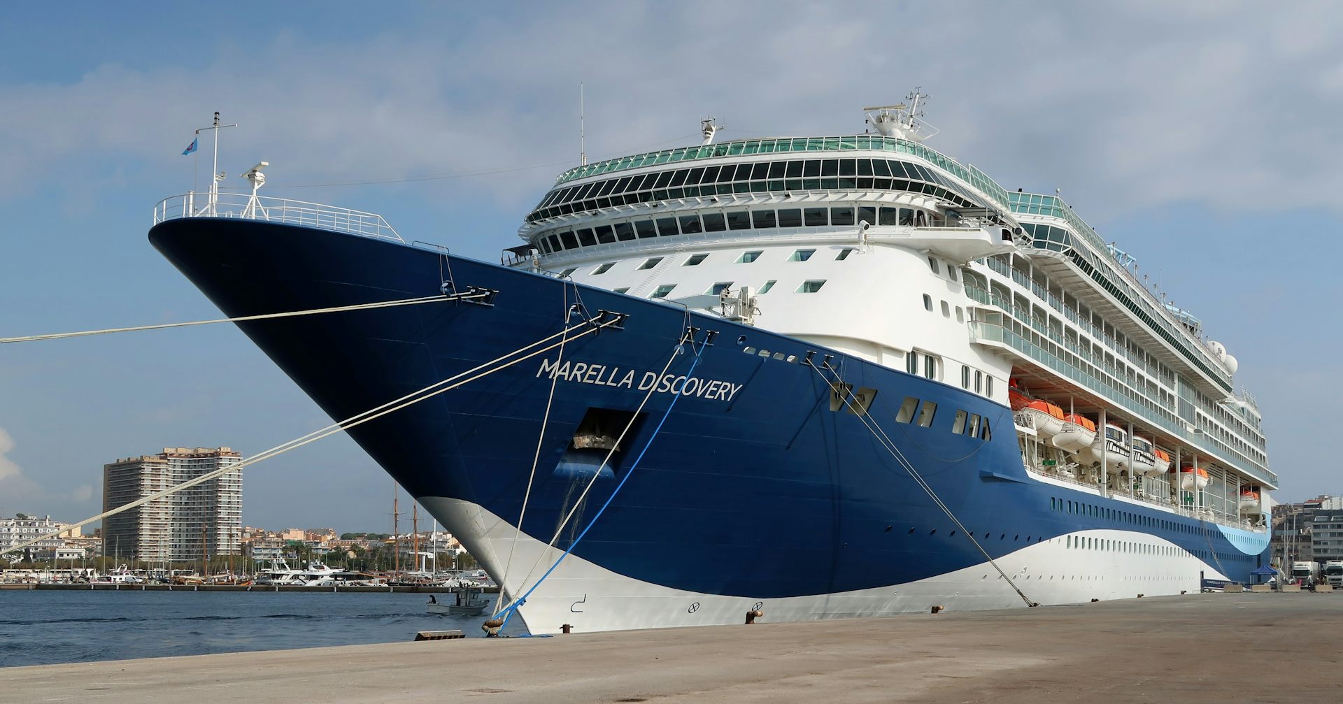 Un barco de crucero amarrado a un muelle con una ciudad de fondo