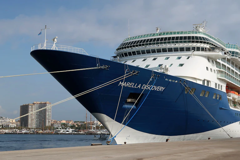 Un barco de crucero amarrado a un muelle con una ciudad de fondo