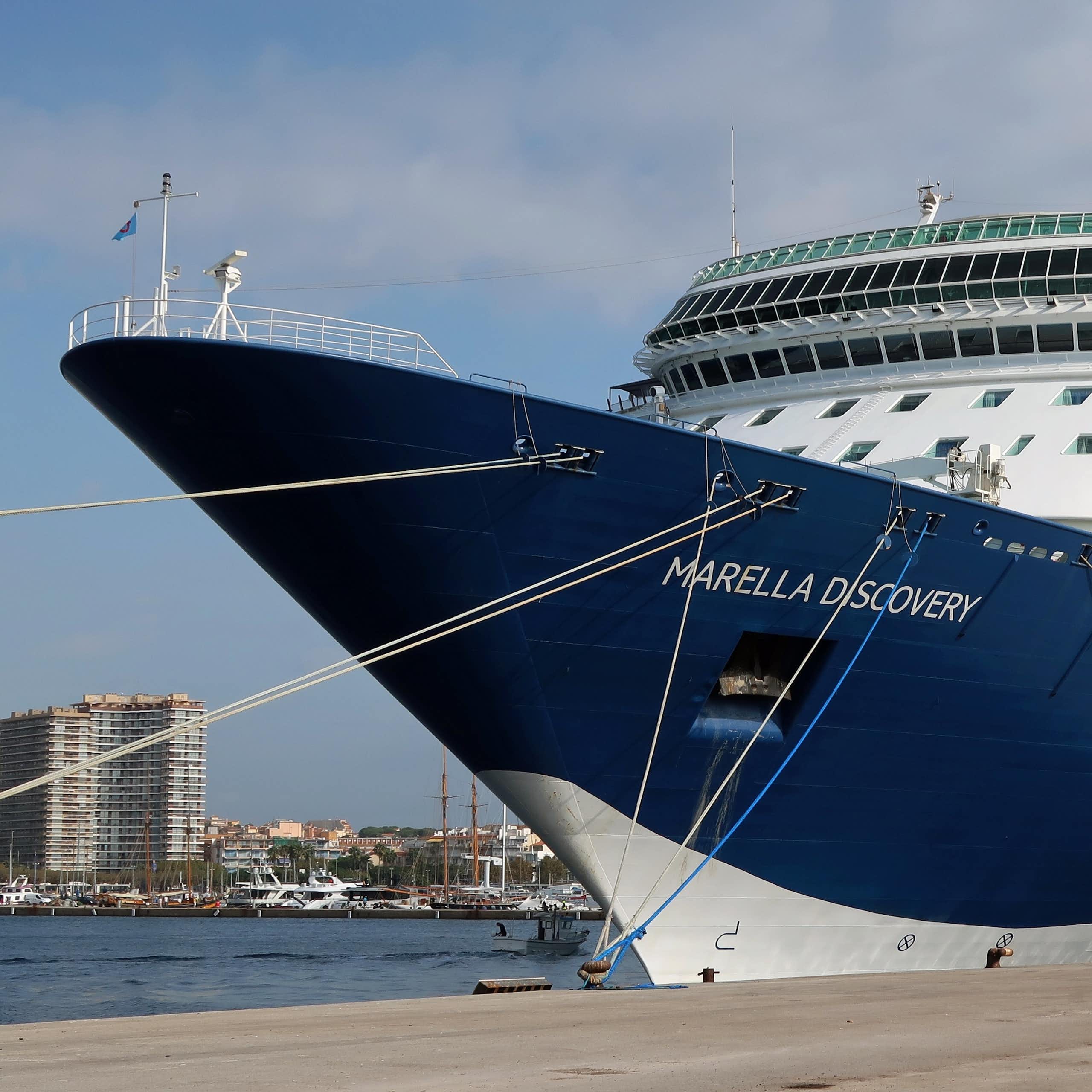 Un barco de crucero amarrado a un muelle con una ciudad de fondo