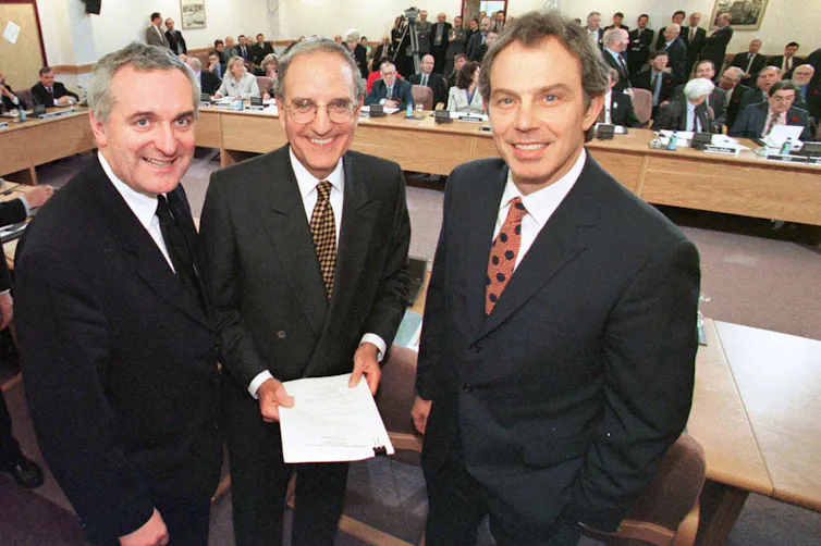 Three men pose together for a photo.