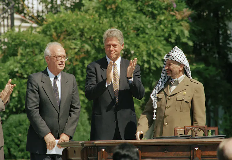 Three men stand together at a ceremony.