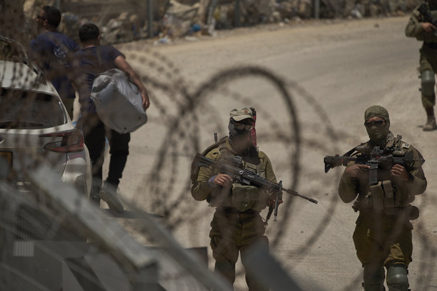 Soldiers stand by barbed-wire fences.