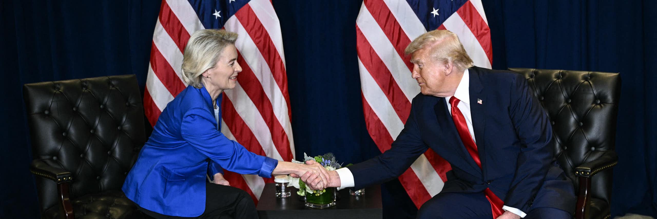European Commission President Ursula von der Leyen, sitting on the left, shakes hands with US President Donald Trump, sitting on the right.