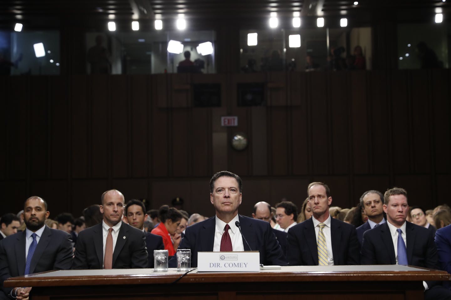 Five men in suits and ties sit at a table.