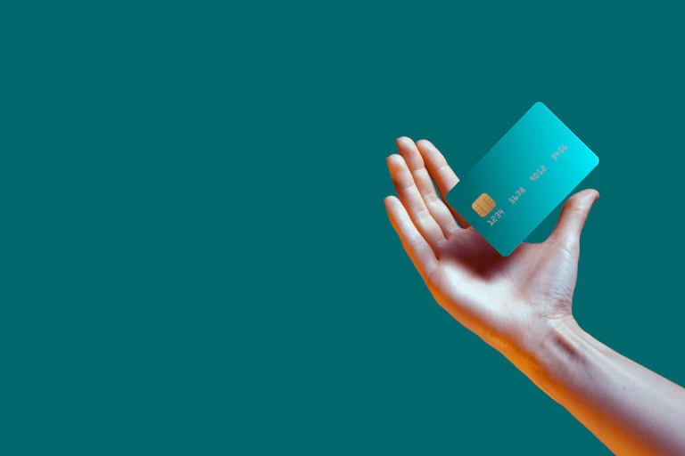 female hand holding a bank card against a green background