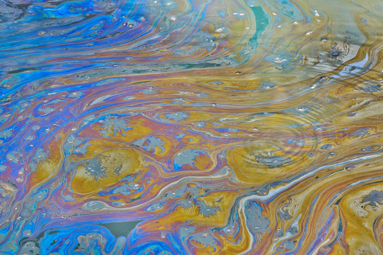 A sheen of chemicals floats atop a waterway.