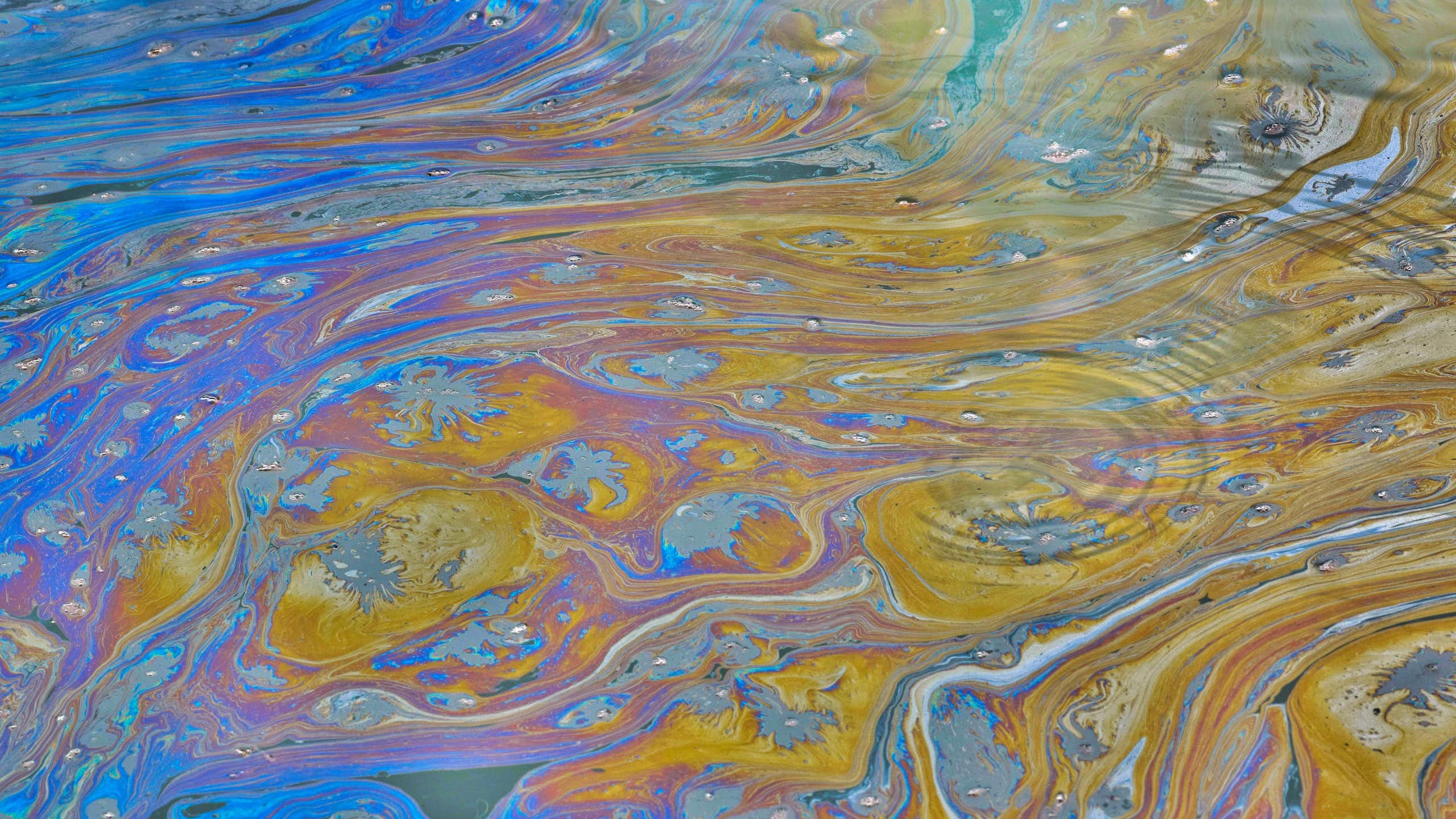 A sheen of chemicals floats atop a waterway.