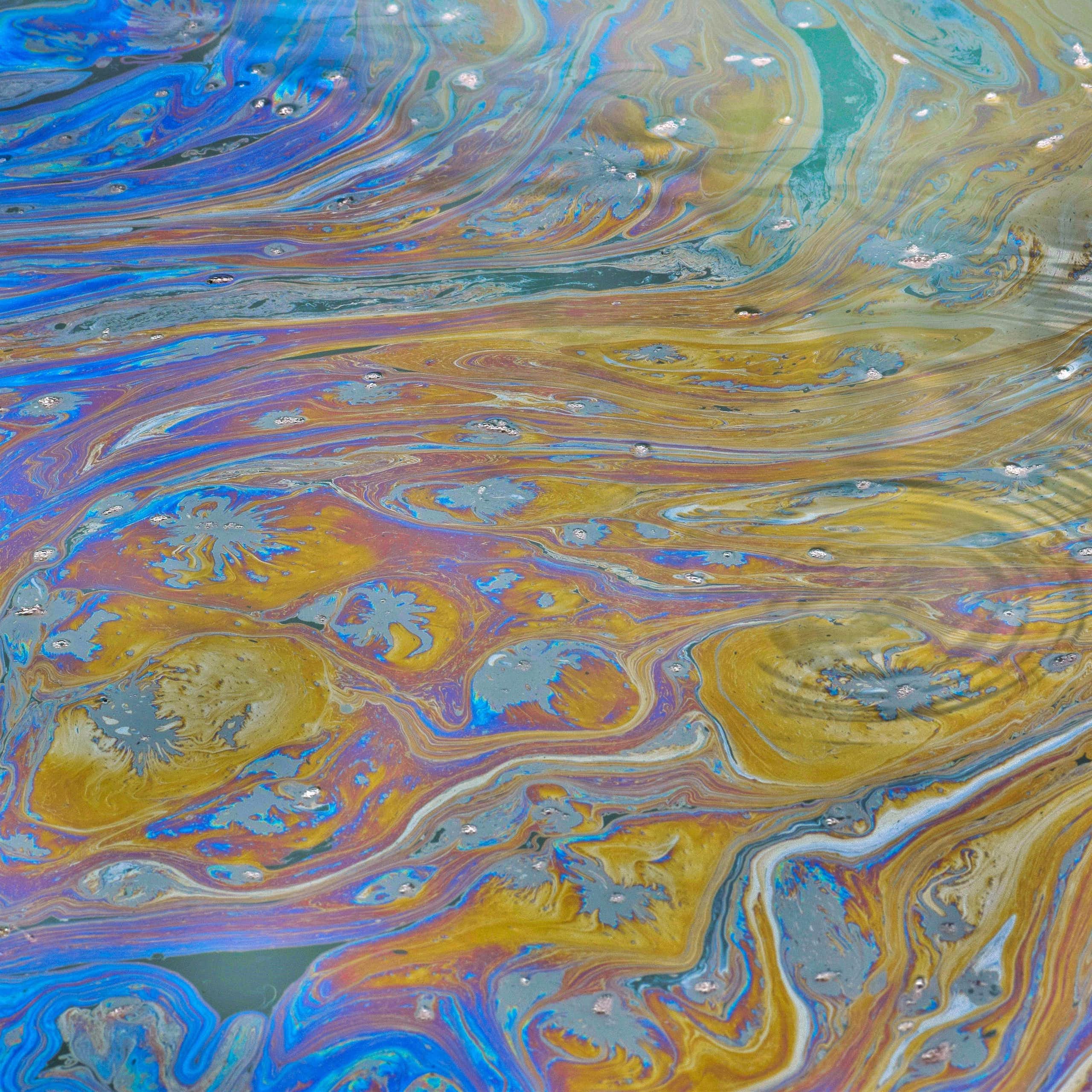 A sheen of chemicals floats atop a waterway.