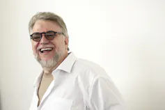 A smiling man in a white jacket.