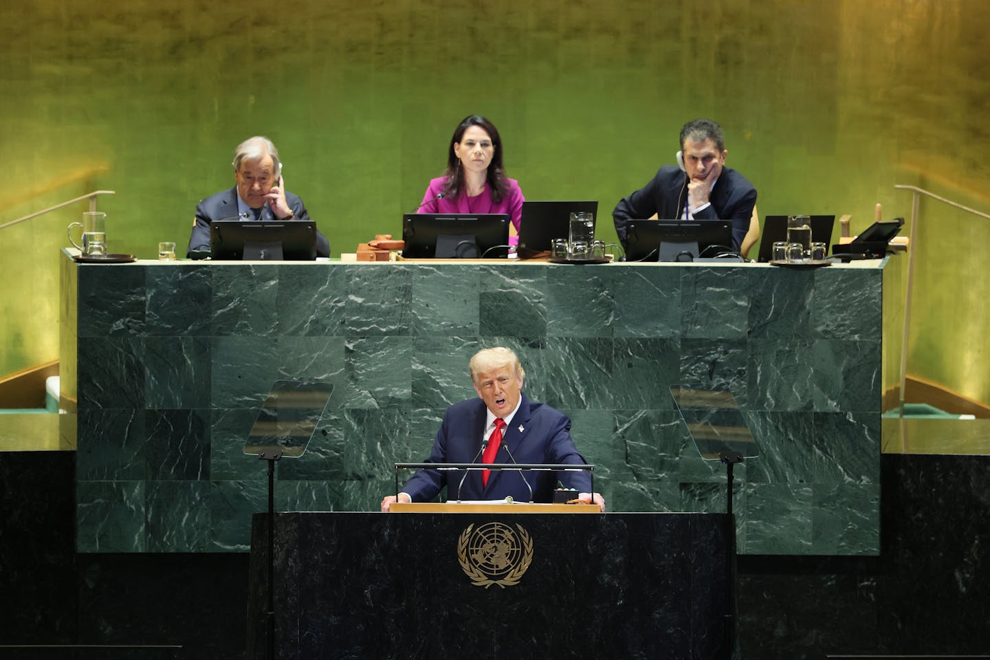 US President Donald Trump addresses the UN, while three dignitaries sit behind him