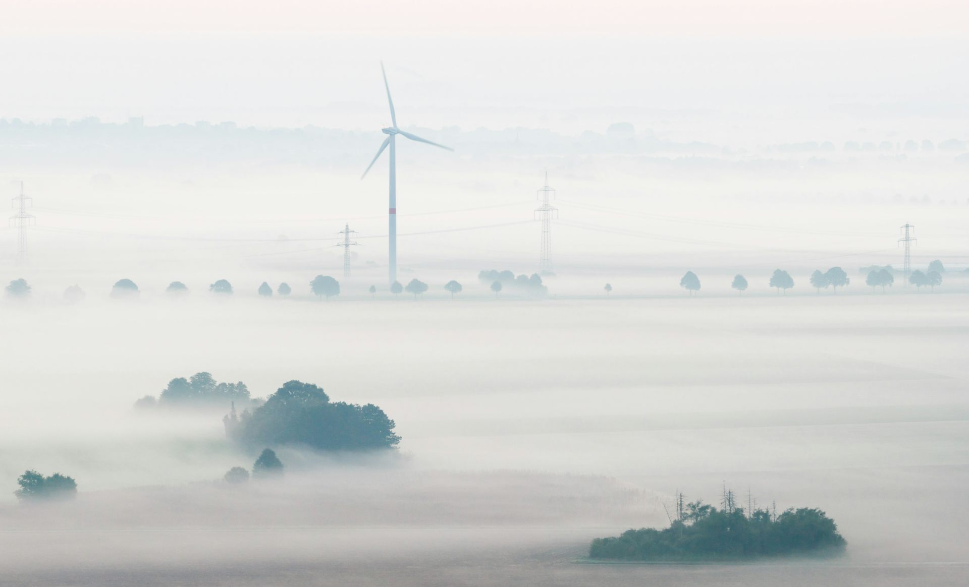 A wind turbine stands in a foggy field in France.