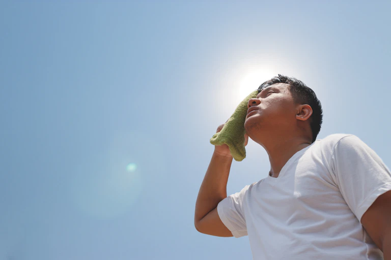 Man dabbing his head on fiercely hot day.