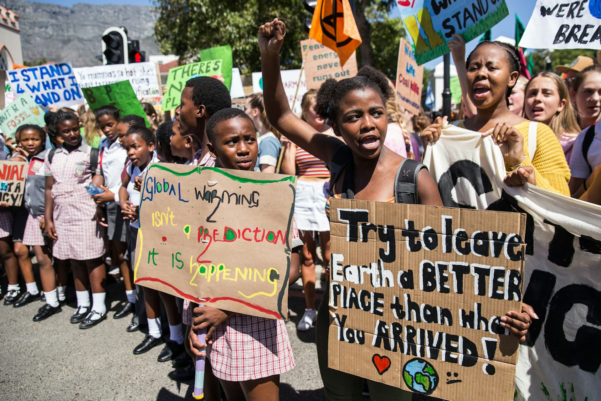 Young children with signs saying "Try to leave Earth a better place than when you arrive" and "Global warming isn't a prediction - it is happening"
