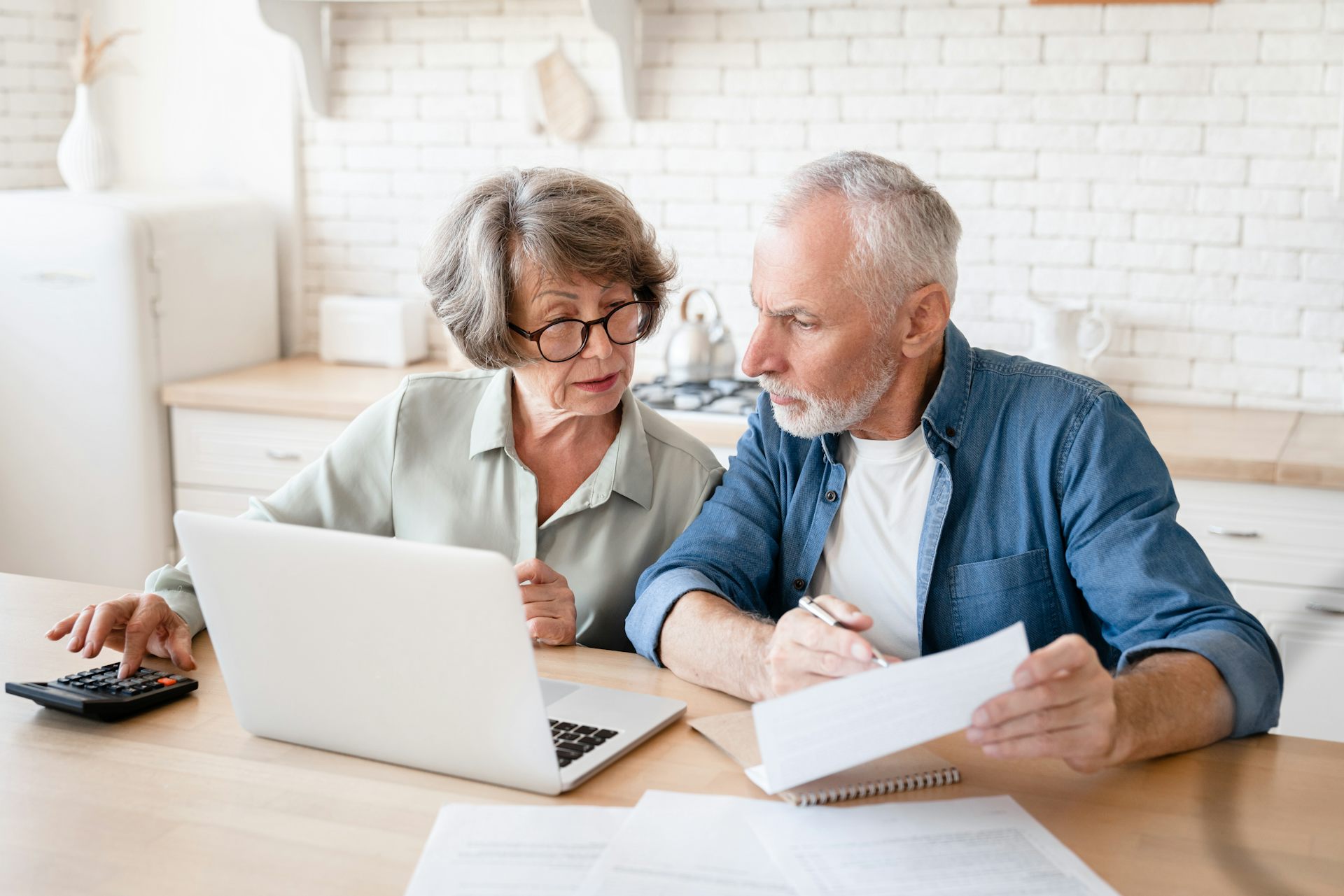 Senior couple looking at a computer screen at the kitchen table.