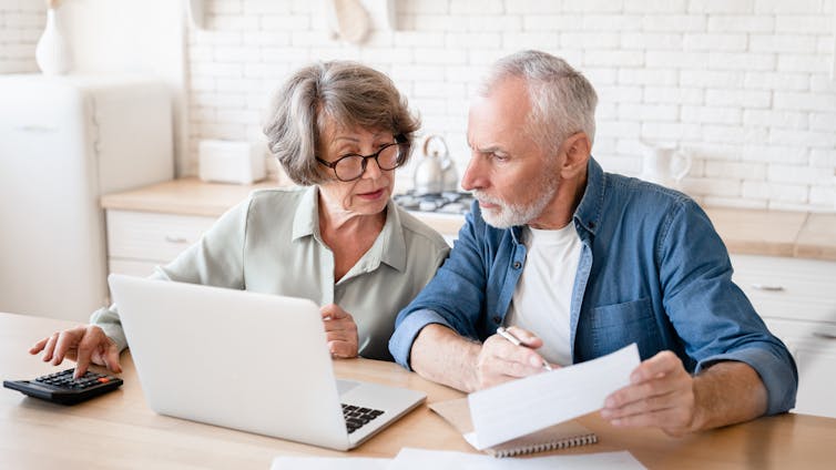 Senior couple looking at a computer screen at the kitchen table.
