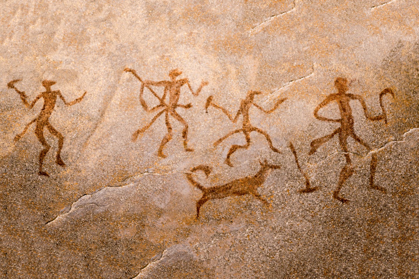Rock painting of prehistoric people hunting together.