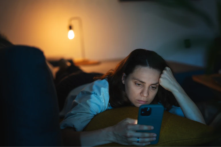 Woman looking at her phone in bed.