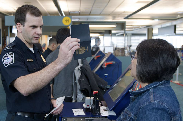A U.S. customs agent talks to a traveller at an airport.