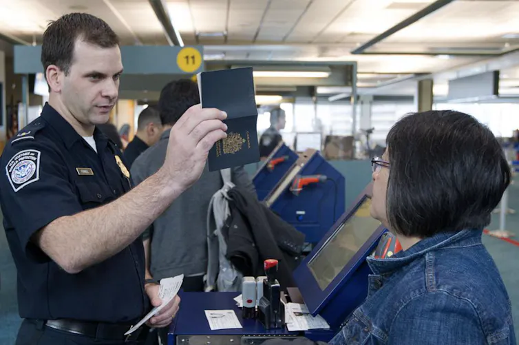 A U.S. customs agent talks to a traveller at an airport.
