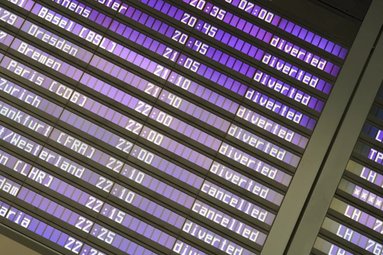 An airport screen shows a long list of diverted flights.