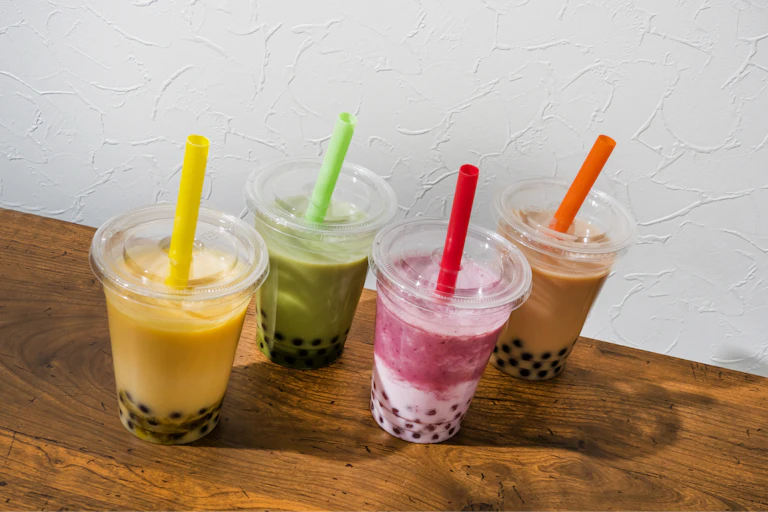 Different flavoured bubble teas on a wooden table.