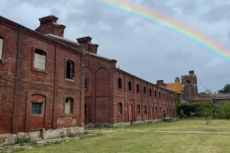 An abandoned building with a rainbow in the sky