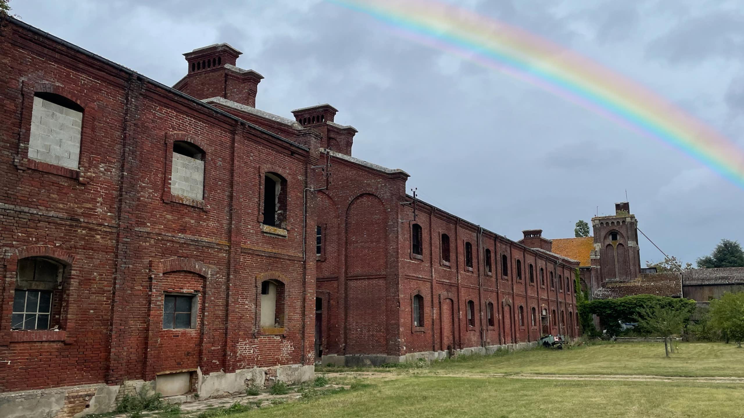 An abandoned building with a rainbow in the sky