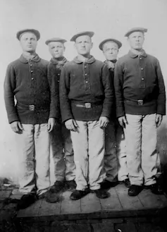 Five teenage boys in uniforms that include berets.