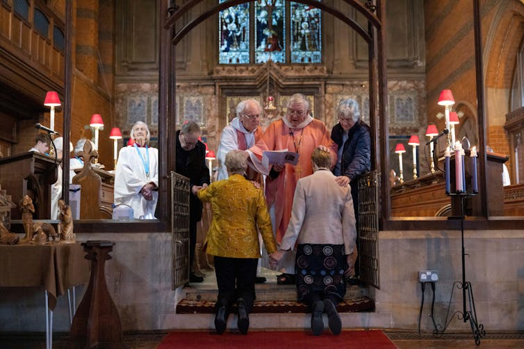 A lesbian couple faces a priest inside st john the baptist church in Felixstowe