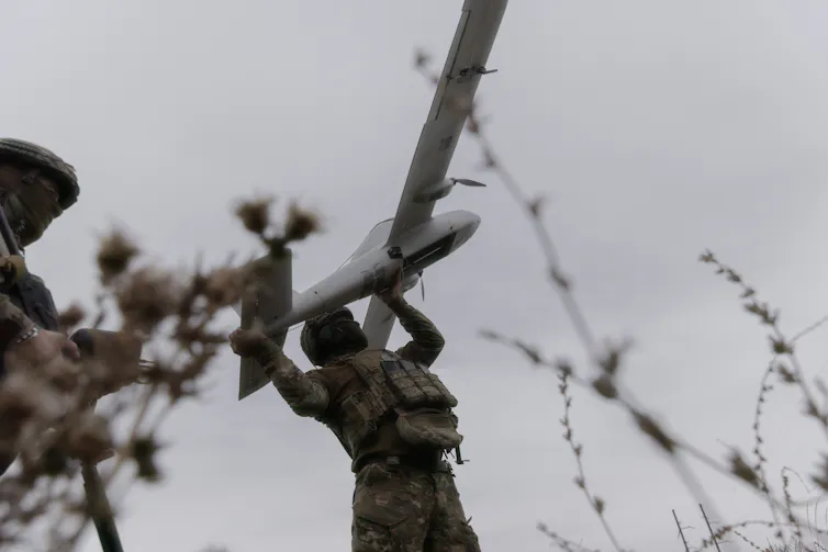 A soldier holds a large drone.
