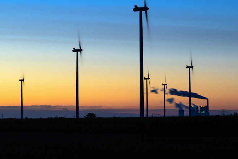 Wind turbines and a coal-fired power plant at sunrise in Germany.