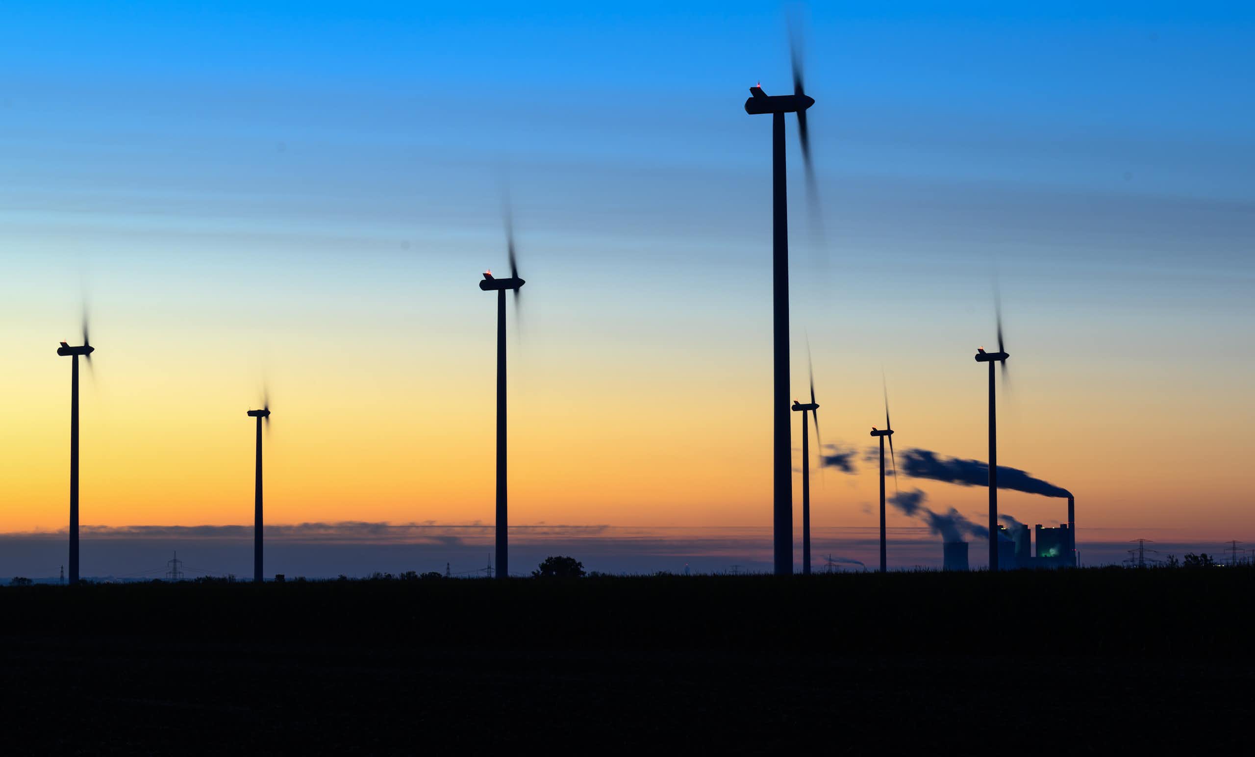 Wind turbines and a coal-fired power plant at sunrise in Germany.