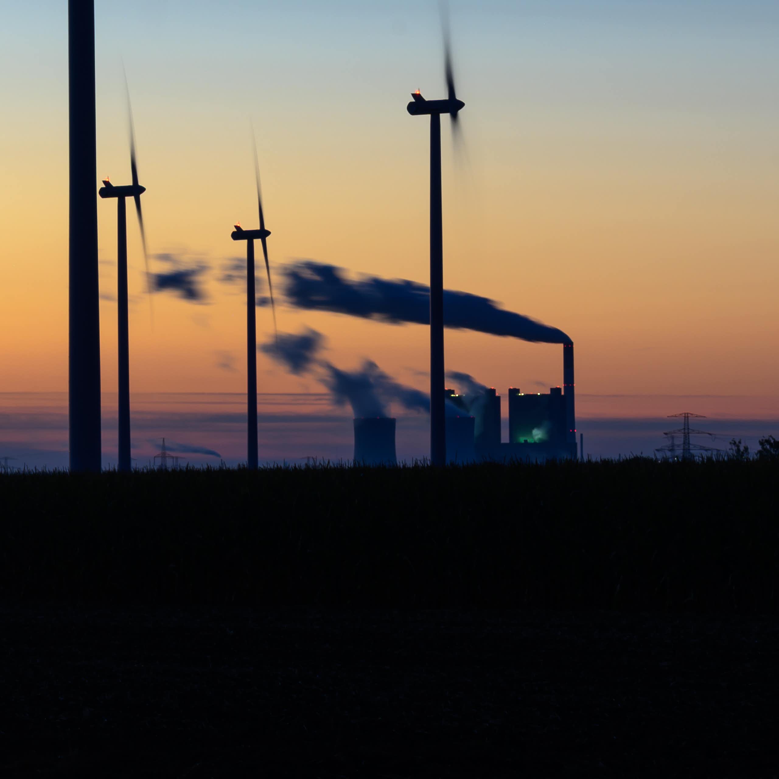 Wind turbines and a coal-fired power plant at sunrise in Germany.