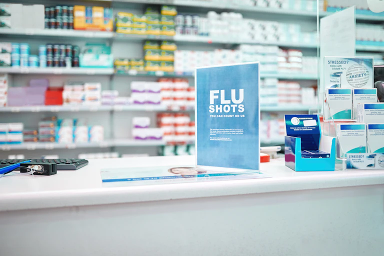 A sign advertising flu shots on the counter of a pharmacy