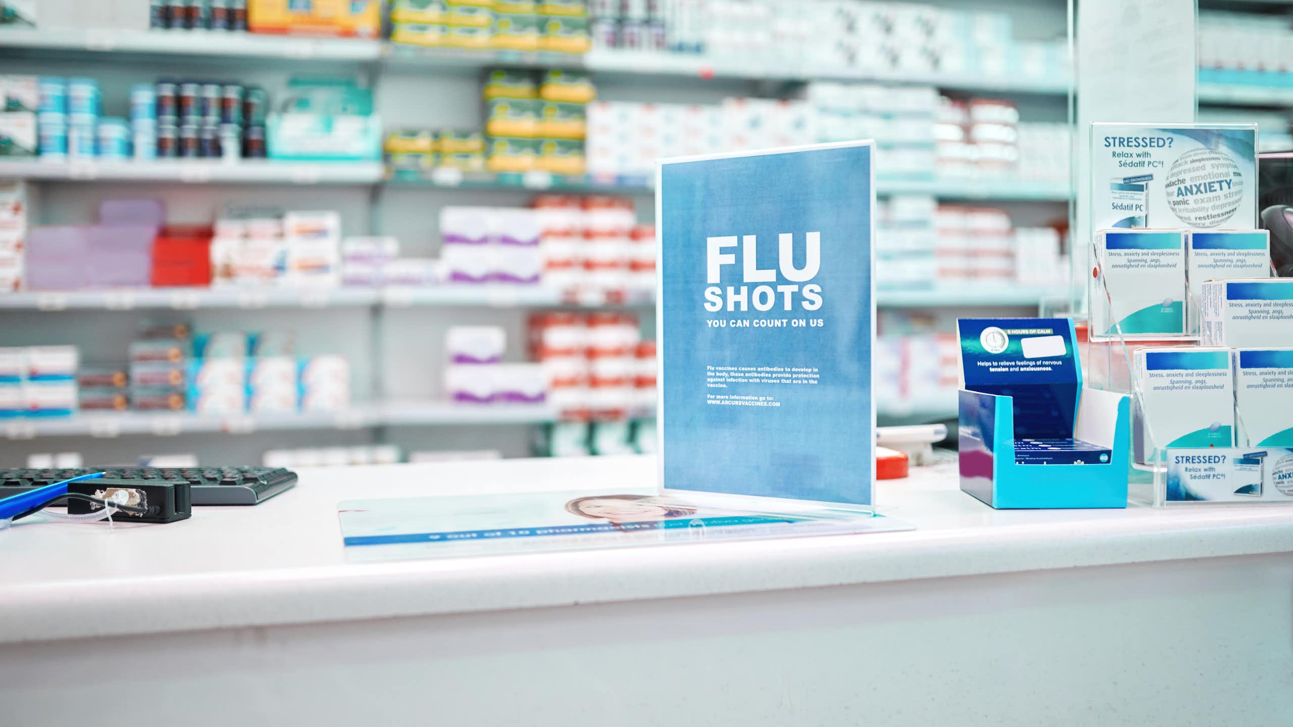 A sign advertising flu shots on the counter of a pharmacy