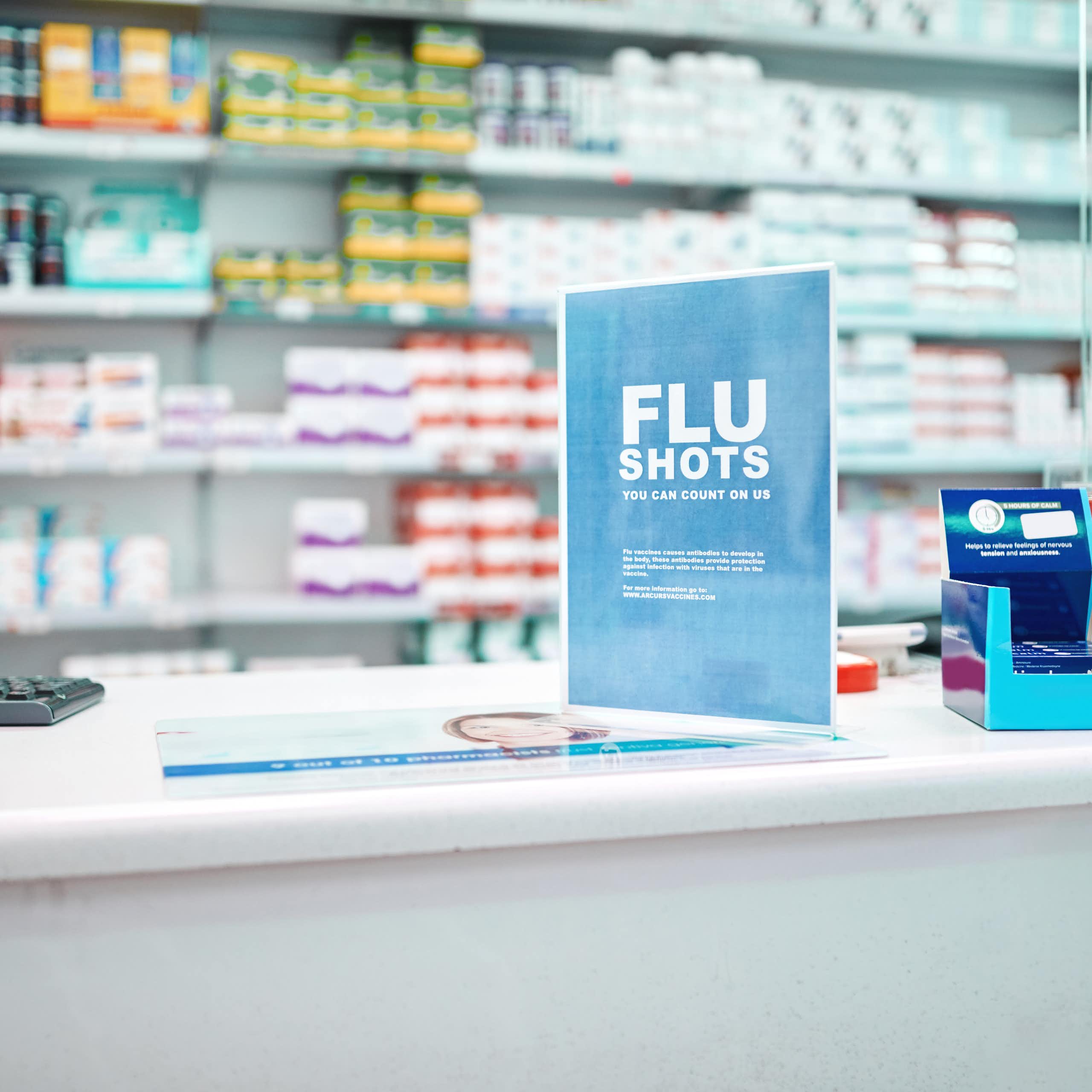 A sign advertising flu shots on the counter of a pharmacy