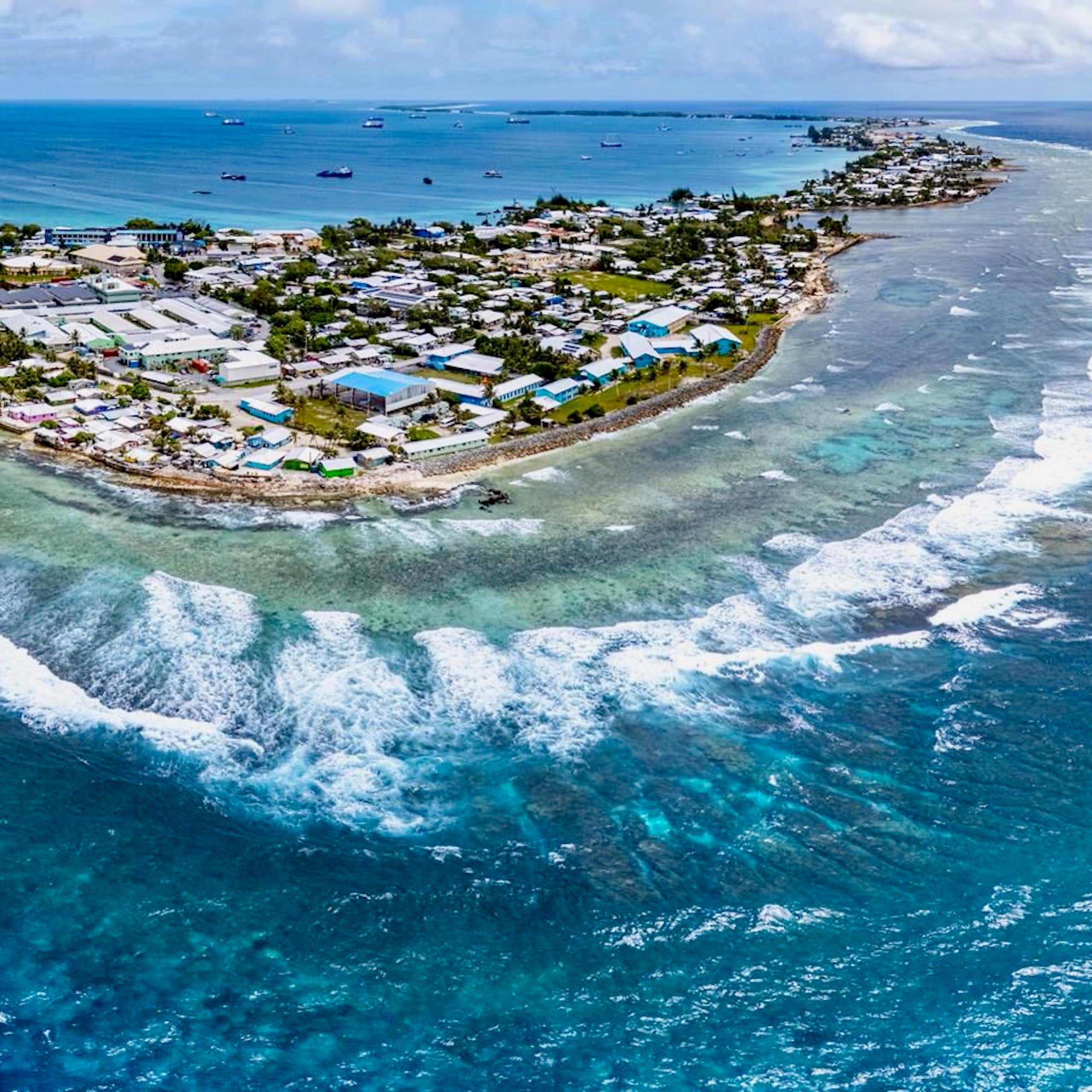 An aerial view of an island filled with buildings. The ocean is a brilliant blue.