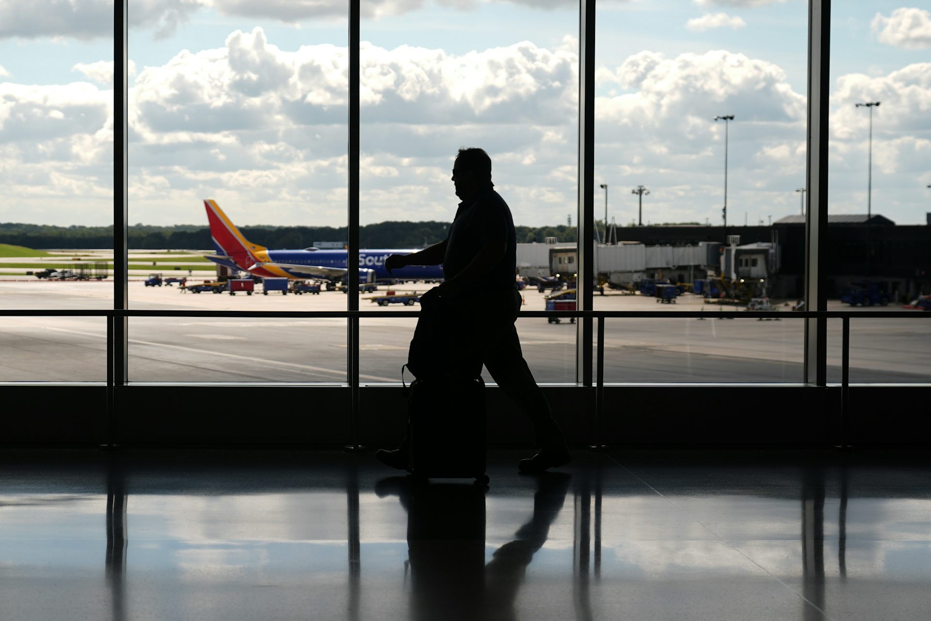 A person walks past a large window at an airport overlooking a plan sitting on the runway