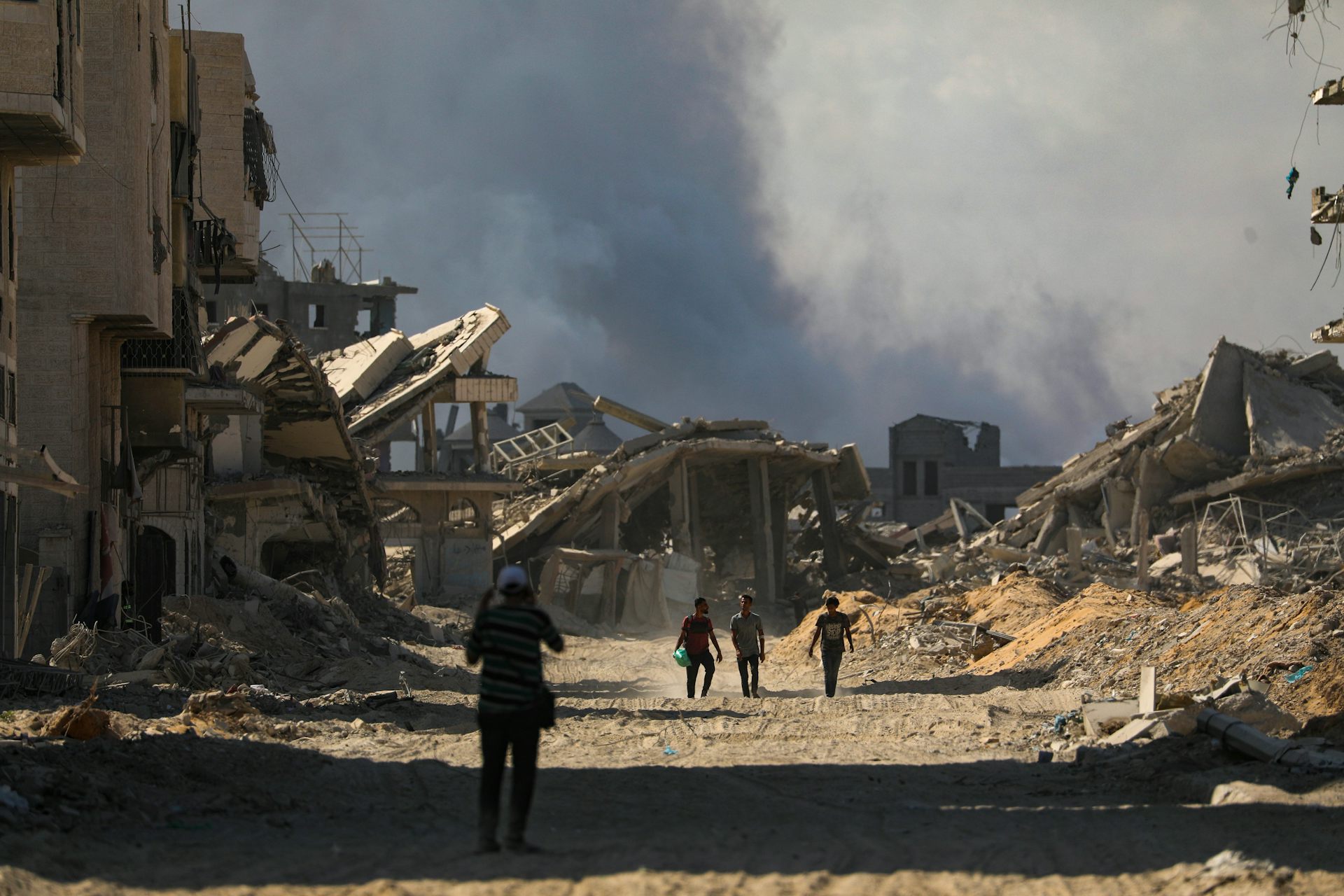 Palestinians walk along a street amid the rubble of destroyed buildings in Gaza.