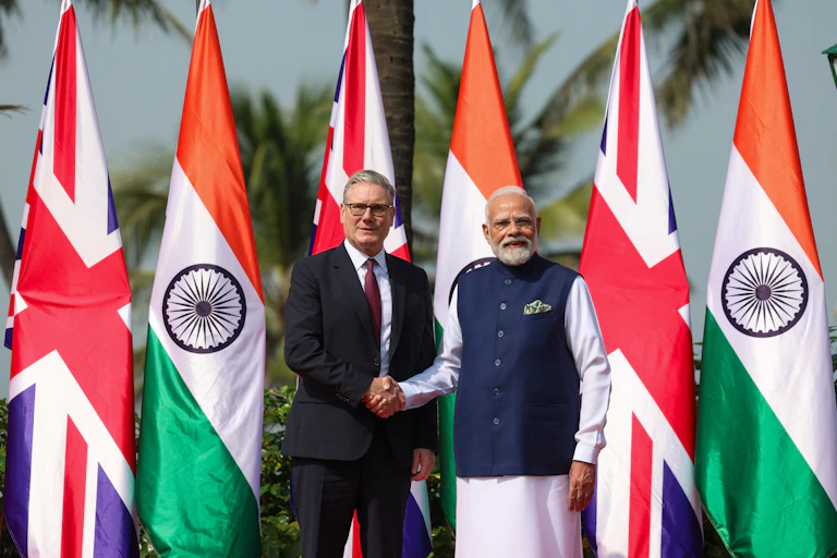 Starmer and Modi shake hands in front of their national flags.
