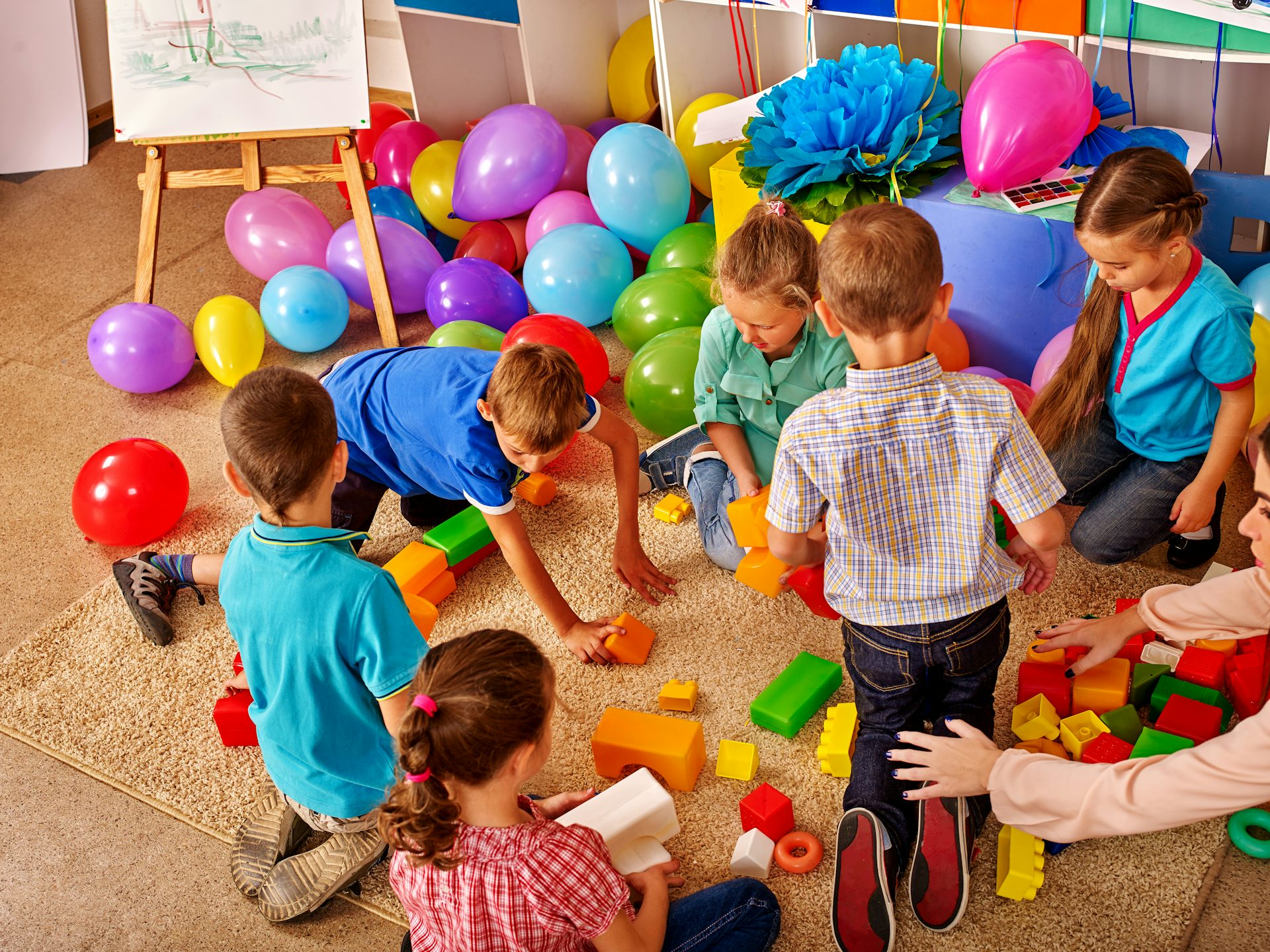 Niños jugando con bloques y globos.