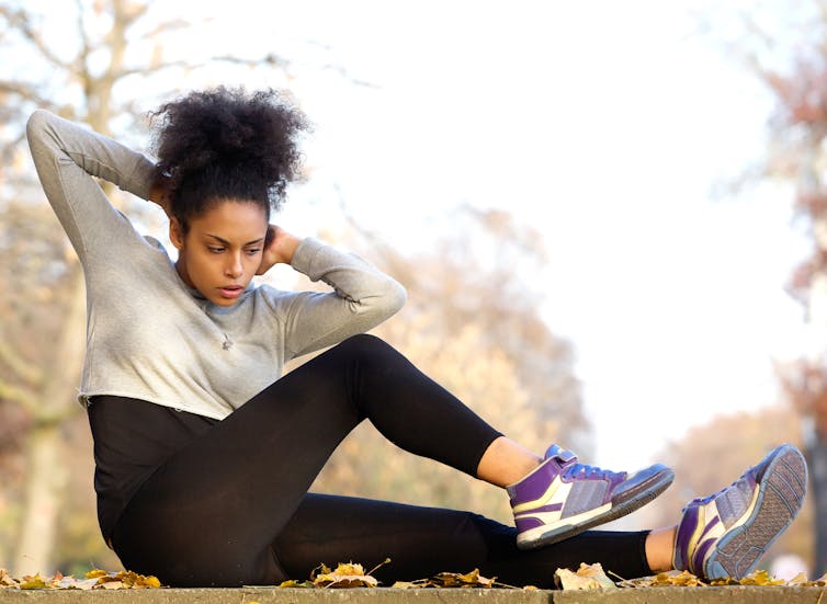 young woman in sports clothing doing exercises in a park.